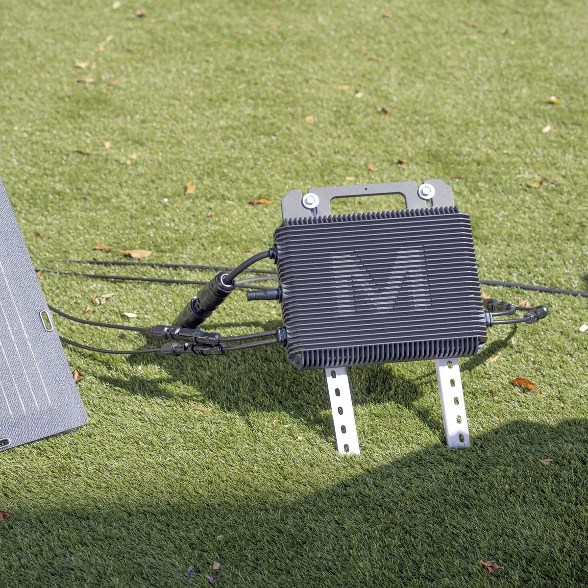 Marstek Mikrowechselrichter aufgeständert neben einem Solarmodul im Garten